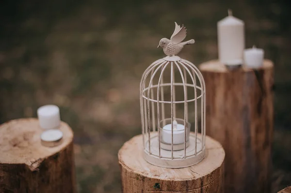 Beyaz dekoratif kafes asılı ve retro ahşap masa ile düşen kuru yapraklar üzerinde yanan mum ile