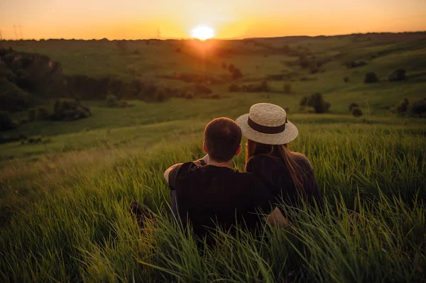 Şık genç çift bir tepede oturan ve gün batımı hayran. Bir ışık ve güneş ışığı ile bir film fotoğrafı, bir yüz olmadan