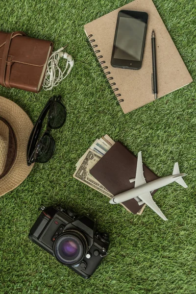 Tourist travel planning concept on grass with passport, airplane, camera, hat and sunglasses. Travel Concept