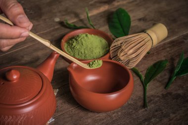 Adam yeşil çay tozu matcha aksesuarları ve yeşil çay kase görünümünü kırpılmış.