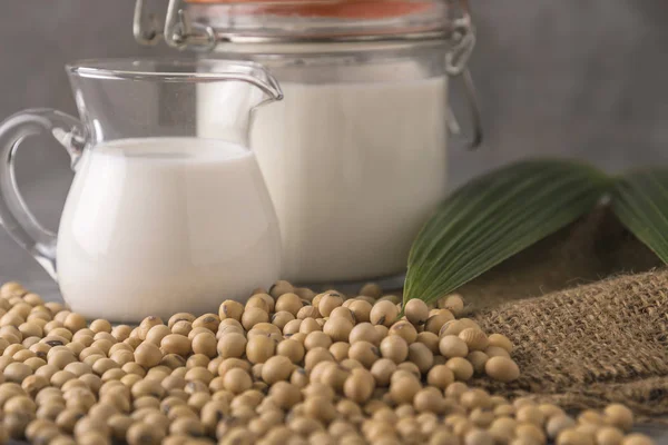 Still life of soybeans and milk in glass jars.