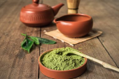Matcha çay toz ve mutfak aksesuar arka plan üzerinde tahta kaşıkla.