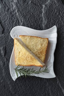 siyah taş zemin üzerine beyaz tabakta tost