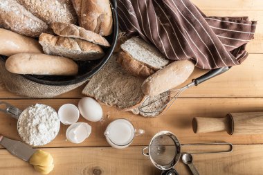 Rustik ekmek ekmek dilimleri ve yumurta ile ahşap masa üzerinde metalik kase çeşitleri bileşimi.