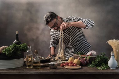 Spagetti mutfak üzerinde hazırlanıyor kareli gömlekli sakallı yakışıklı cheef.