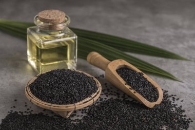 Siyah susam yağı ve kahverengi zemin üzerine yeşil yaprakları ile kompozisyon.