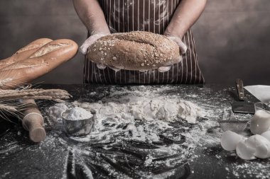 Adamın elinde masada holding ekmek hazırlama kırpılmış görünümü.