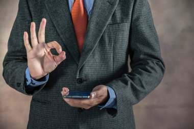 Cep telefonuyla ok işaret gösteren işadamı el.