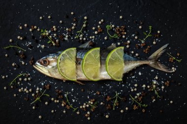 Limon dilimleri, deniz tuzu ve karabiberi siyah arka plan üzerine ile ham uskumru.