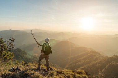 Fotoğrafçı dağın zirvesinde elinde kamera ile. 