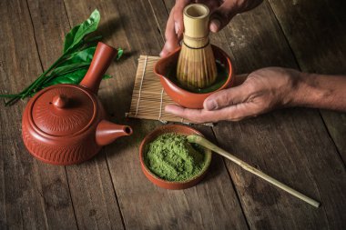 Adam yeşil çay tozu matcha aksesuarları ve yeşil çay kase görünümünü kırpılmış.