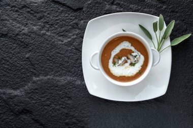 Kara taş yüzeyi beyaz kase karides ile krem çorbası üstten görünüm.