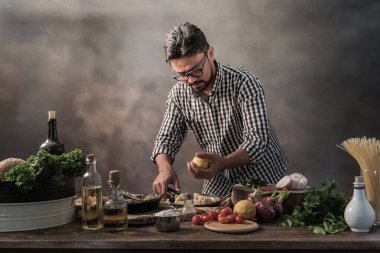 Sakallı genç mutfak spicing spagetti yemek.