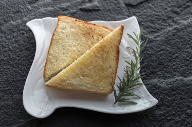 siyah taş zemin üzerine beyaz tabakta tost