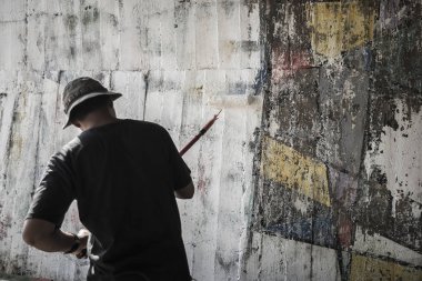 Genç adam şapka boyama beyaz renkli eski çimento duvarın, Tayland üzerinden.