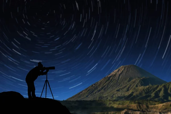silhouette of photographer shooting star trail on background