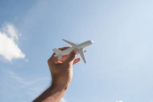 Airplane model in human hand on sky background