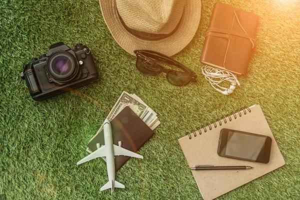 Tourist travel planning concept on grass with passport, airplane, camera, hat and sunglasses. Travel Concept