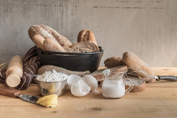 Different kinds of bread with milk and eggs on wooden table.