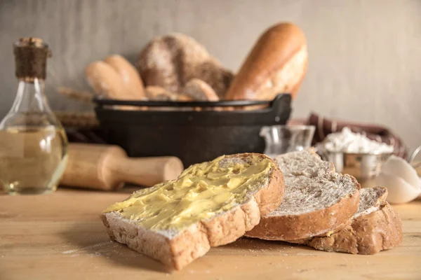 Making bread. Rustic style, Different kinds of bread rolls on table with bread slices and butter on top.