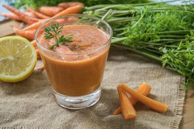 Rustik ahşap masa üzerinde taze havuç güler yüzlü cam görünümü Kapat.