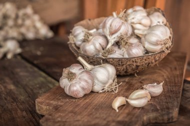 Hindistan cevizi kabuk ahşap tahta üzerinde sarımsak ampuller.