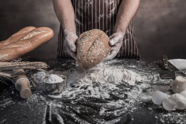 Erkek aşçı taze pişmiş ekmek elinde tutan görünümünü kırpılmış.