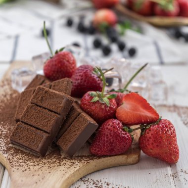 Ahşap tahta üzerinde çikolata parçaları ile taze çilek görünümü Kapat