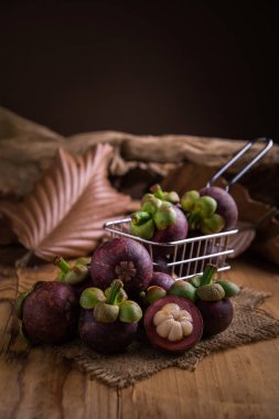 Ahşap masa üzerinde küçük alışveriş sepeti içinde mangosten meyve