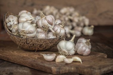 Hindistan cevizi kabuk ahşap tahta üzerinde sarımsak ampuller.