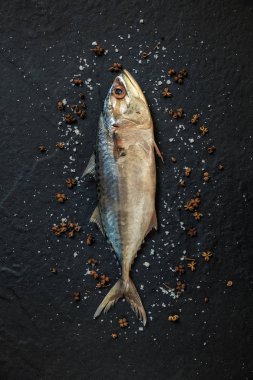 Deniz tuzu ve siyah arka plan üzerine biber ile taze, çiğ uskumru.