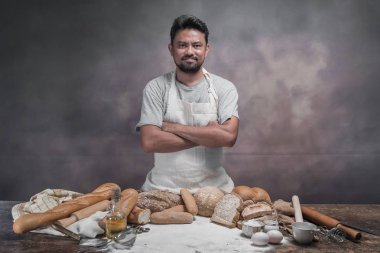Taze pişmiş ekmeği ve ekmek ile masada duran mutlu Asya aşçı.