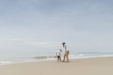 Küçük oğlu gri gün sahilde yürüyüş kadınla