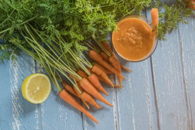 Havuç ve limon ile rustik ahşap masa üzerinde taze havuç güler yüzlü cam üstten görünüm.