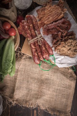 Ev yapımı ekmek dilimlenmiş jambon, sosis ve ahşap masa sebze ile.