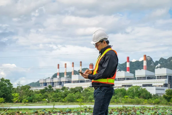Kömür santralı üzerinde arka plan, Tayland ile Smartphone kullanarak mühendisi.