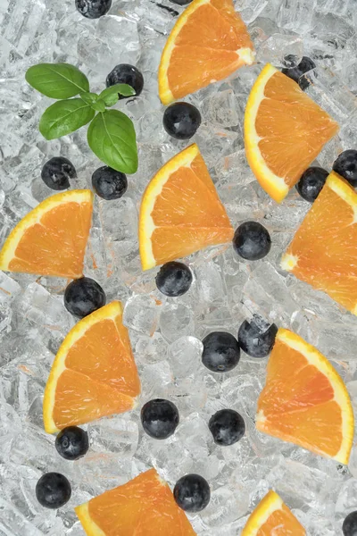 Schließen Sie Die Aufgeschnittene Orange Mit Blaubeeren Auf Eis Hintergrund — Stockfoto