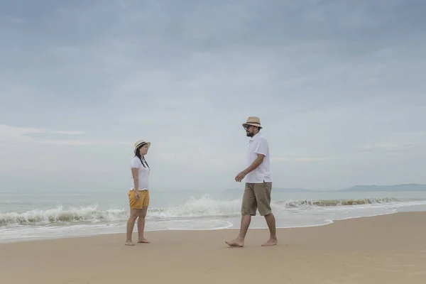 Asian couple walking together by beach