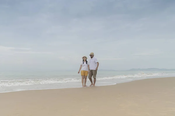 Asian couple walking together by beach