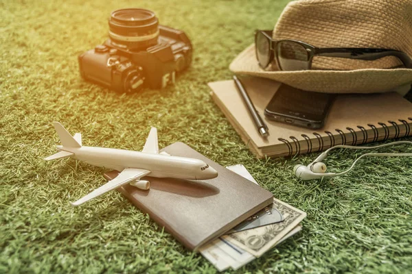 Tourist travel planning concept on grass with passport, airplane, camera, hat and sunglasses. Travel Concept