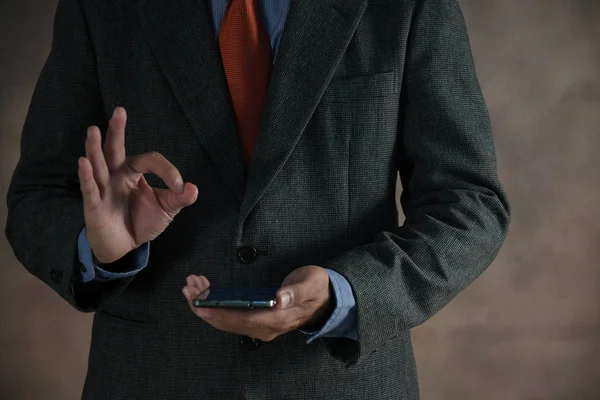 Cep telefonuyla ok işaret gösteren işadamı el.