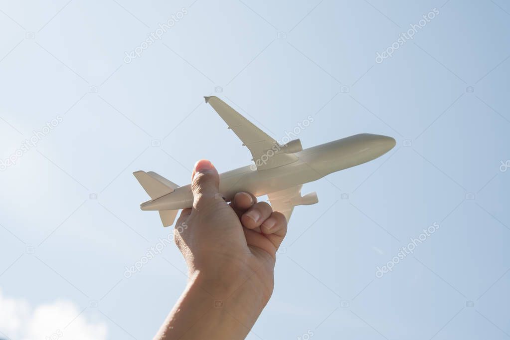 Airplane model in human hand on sky background