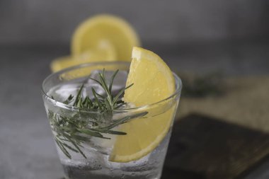 Tablo üzerinde alkollü içki cin tonik limon, biberiye ve buz ile görünümü Kapat.