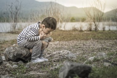 Sevimli küçük Asya çocuk taşları, Tayland üzerine oturan bir oyuncak ayı ile.