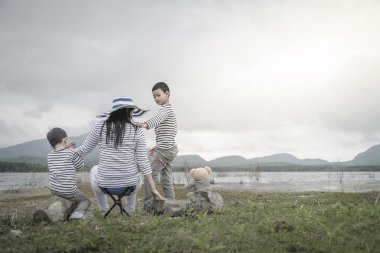 Asyalı kadının oğulları sahilde birlikte ayakta arkadan görünüş