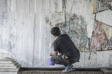 Genç adam boyama beyaz üzerinde eski çimento wall Street'te, Tayland.