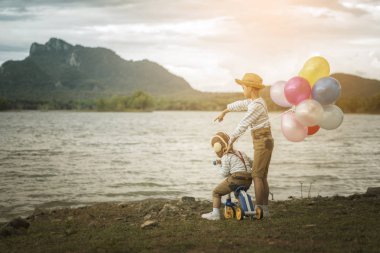 Sahilde küçük kardeşlerin balonlu arkadan görünüş.