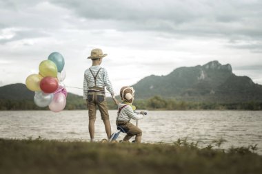 Sahilde küçük kardeşlerin balonlu arkadan görünüş.