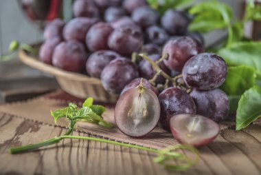 Ahşap masa yemeye hazır üzerinde hasır plaka sağlıklı kırmızı üzüm görünümü Kapat.