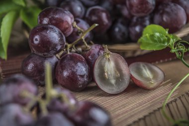 Ahşap masa yemeye hazır üzerinde hasır plaka sağlıklı kırmızı üzüm görünümü Kapat.